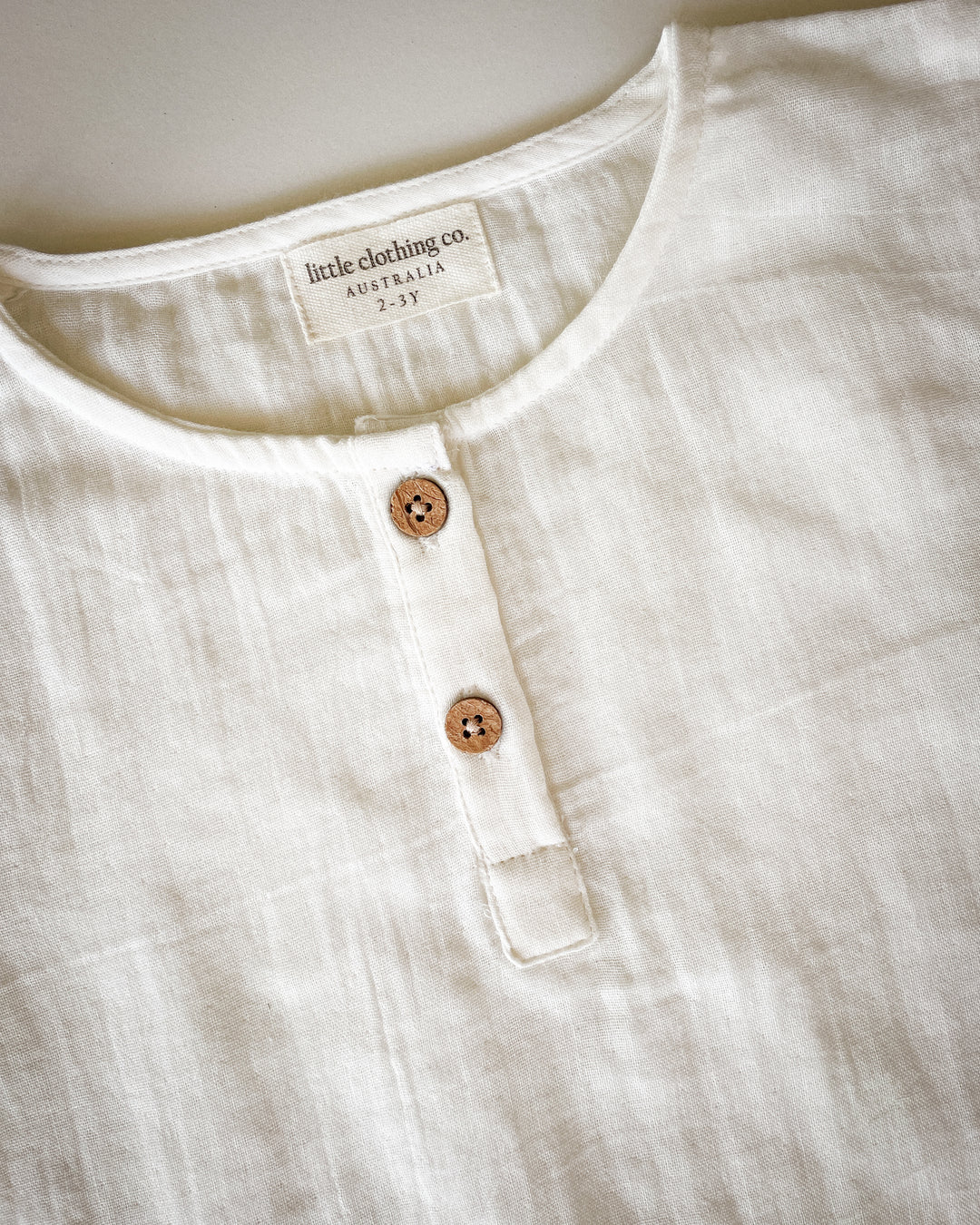 Close-up of a white shirt with buttons and 'little clothing co.' label.